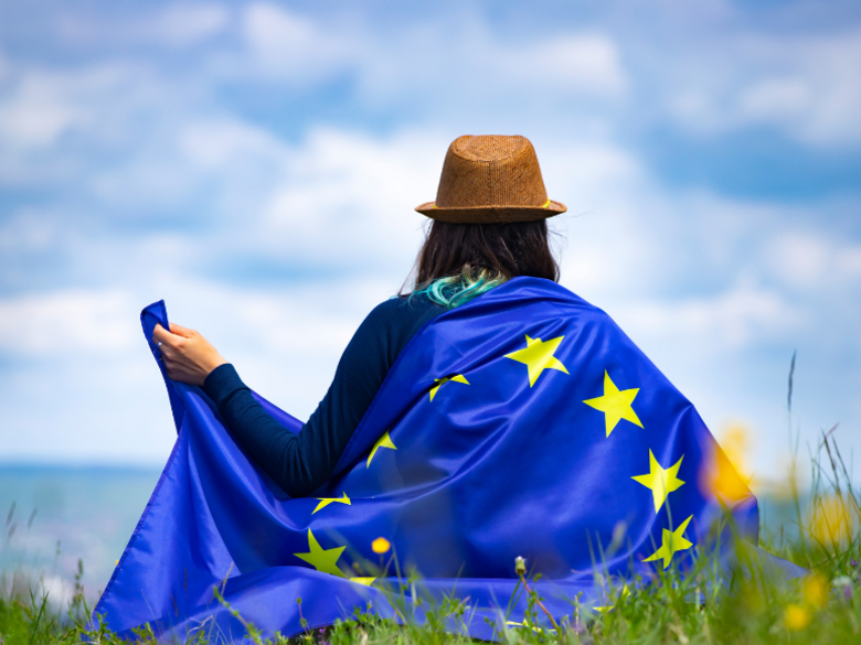 A person photographed from behind with the EU flag around their shoulders.
