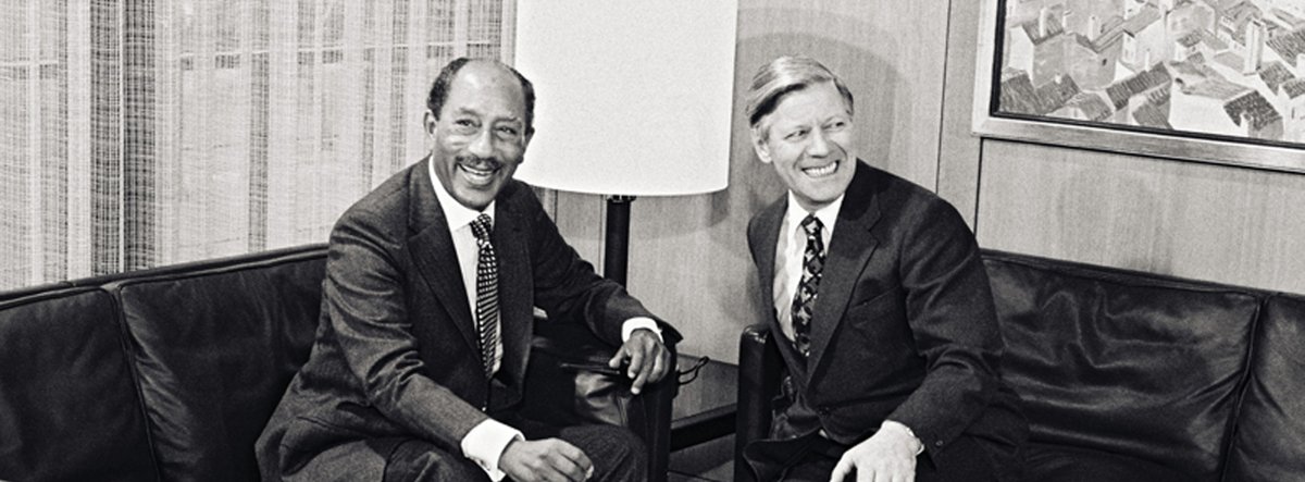 Anwar alSadat und Helmut Schmidt sitzen auf Ledersesseln und lächeln.