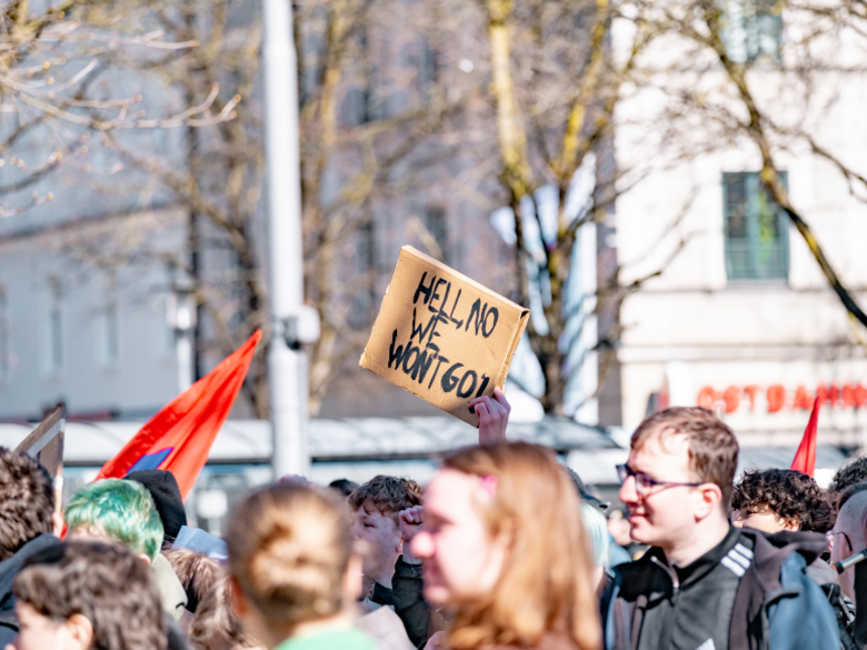 Picture of a demonstration displaying peole, posters and flags