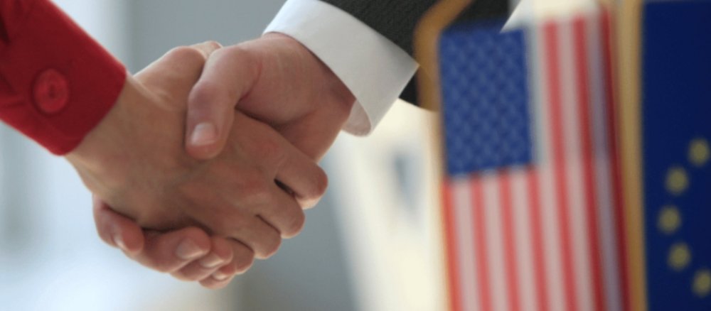 Handschlag mit Europa und USA Flagge im Vordergrund