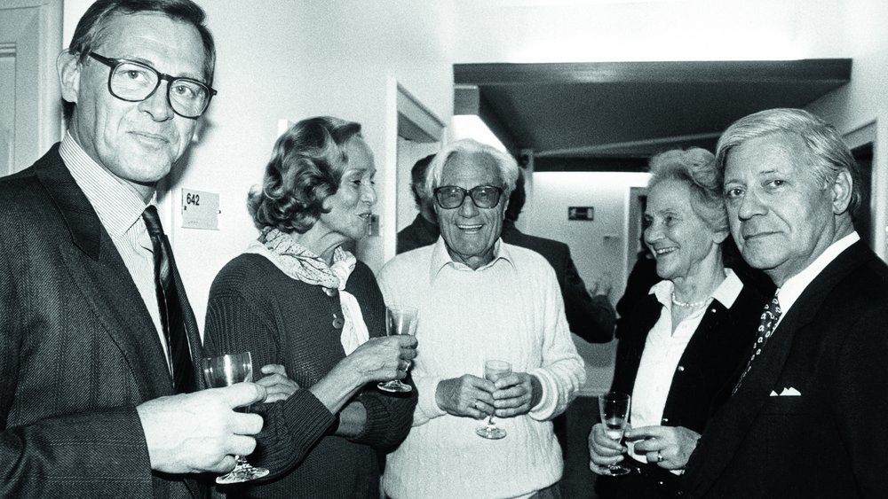 Black-and-white photo of three men and two women holding champagne glasses.