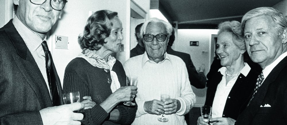 Black-and-white photo of three men and two women holding champagne glasses.