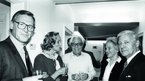 Schwarz-weiß Foto von drei Männern und zwei Frauen mit Sektgläsern in der Hand.