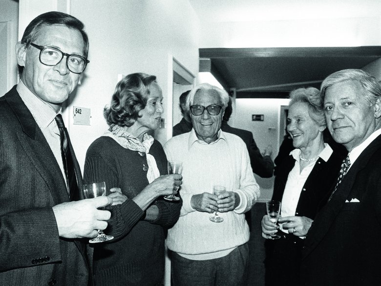 Black-and-white photo of three men and two women holding champagne glasses.