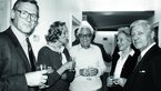 Black-and-white photo of three men and two women holding champagne glasses.