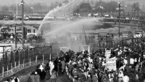 Black and white shot of water cannon throwing water into crowd of demonstrators
