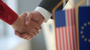 Handshake with Europe and USA flag in the foreground