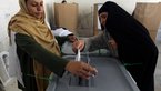 Election worker and woman inserting ballot paper into ballot box