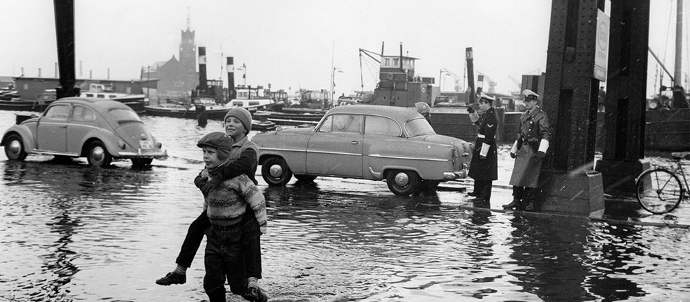 Überschwemmtes Stadtgebiet, Menschen und Autos stehen im Wasser
