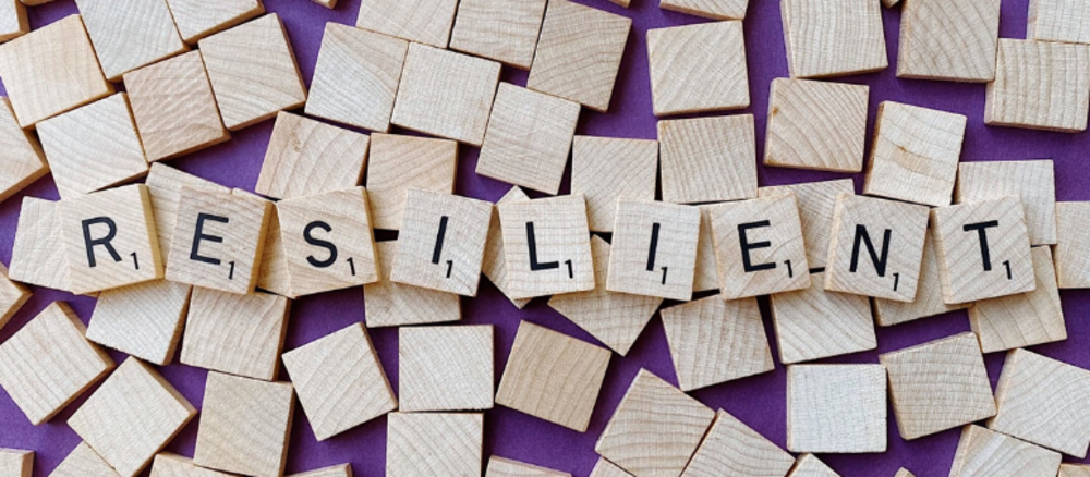 Holzklötze mit Buchstaben aneinandergereiht zum Wort "Resilient"