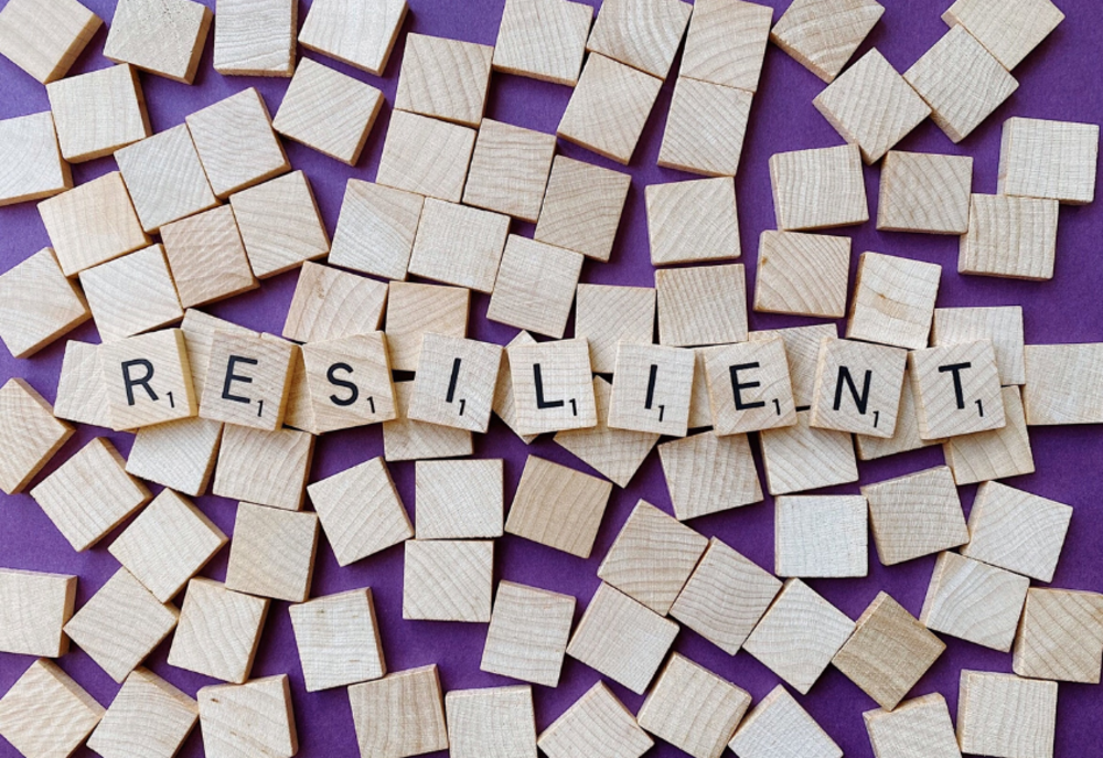Holzklötze mit Buchstaben aneinandergereiht zum Wort "Resilient"