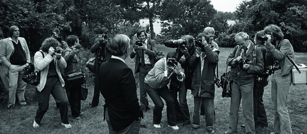 Black and white Photo of Helmut Schmidt, standing in front of many photographers