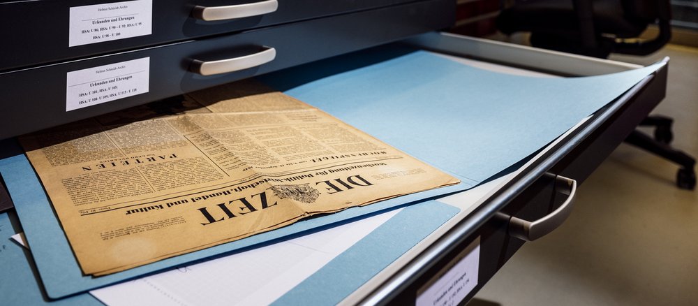 Zeitung liegt in einer geöffneten Schublade eines Archivschrankes