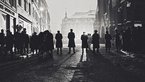Black and white shot of a row of people in a street from behind