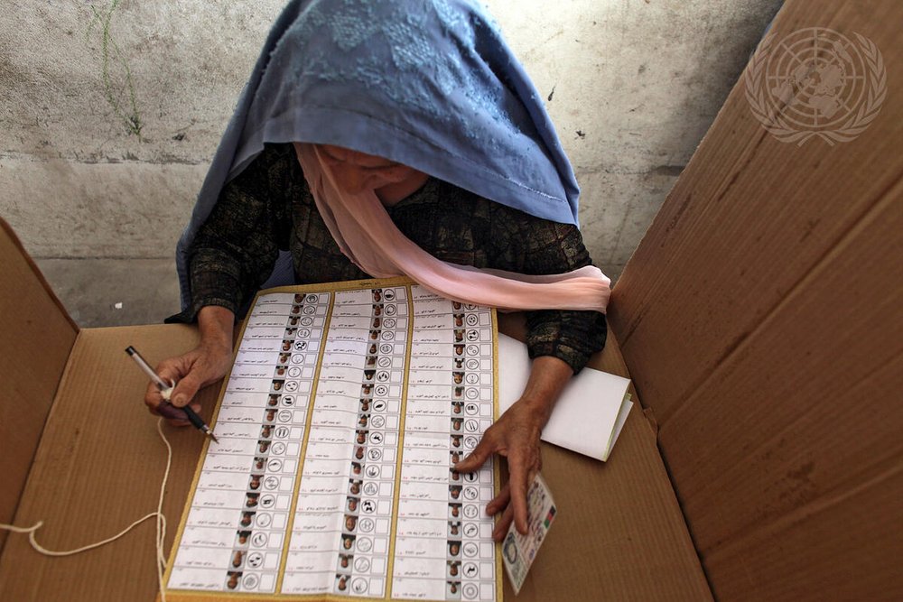 Elderly Afghan woman filling in a ballot paper