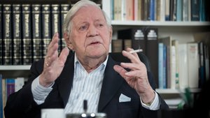 Farbfoto: Helmut Schmidt in seinem Büro vor Bücherregalen, erklärt etwas mit erhobenen Händen; eine Zigarette zwischen den Fingern.