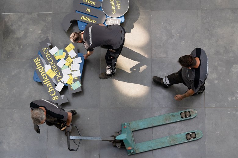 Drei Menschen bauen Ausstellungsobjekte ab