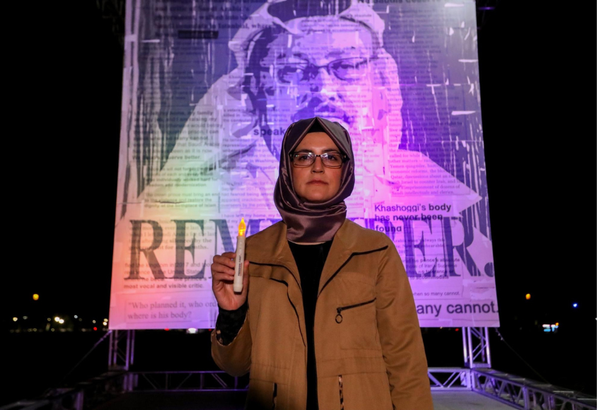 Hatice Cengiz steht mit einer Kerze in der Hand vor einem großen Plakat, das ihren Verlobten Jamal Khashoggi mit der Aufschrift „remember“ zeigt.
